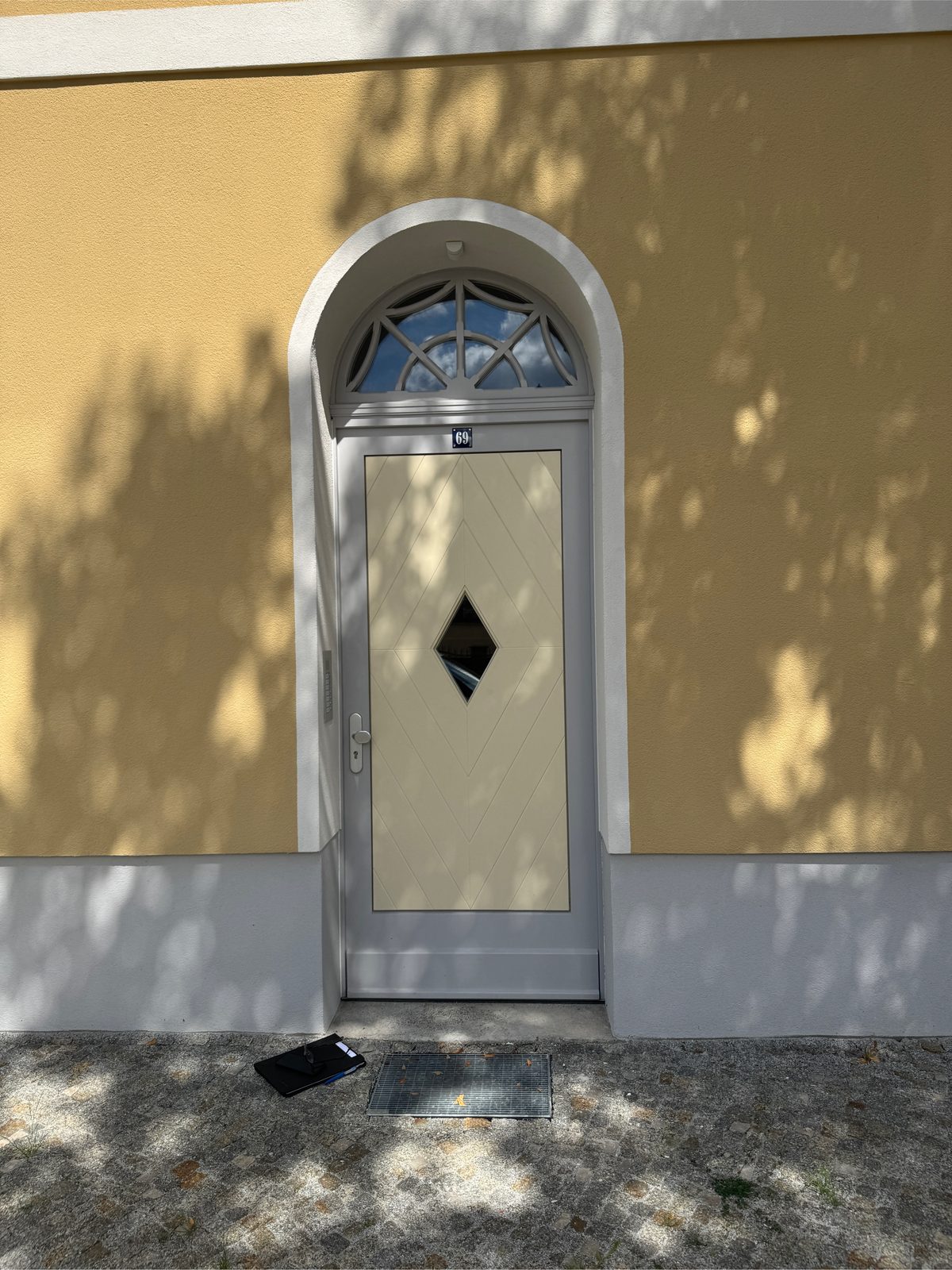 Neue Hauseingangstür mit Rundbogen-Oberlicht in gelber Fassade